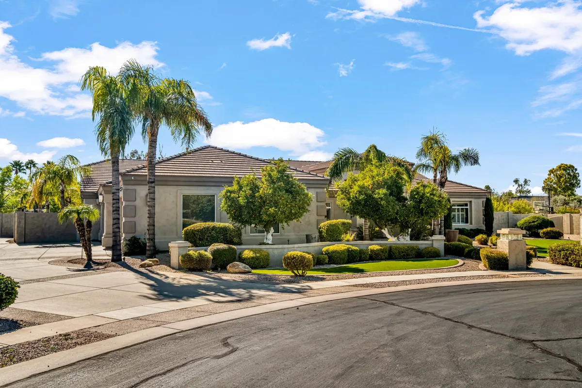 The villa’s elegant exterior featuring modern architectural lines, a circular driveway, well-manicured shrubs, and towering palm trees. This wide-angle view conveys arrival, first impressions, and the resort-like feel of the entire property.