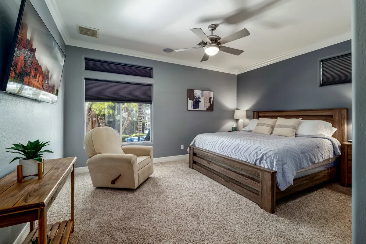 A cozy king bedroom with inviting bedding, an armchair, and decorative artwork. Abundant natural light fills the space, creating a restful and welcoming environment.