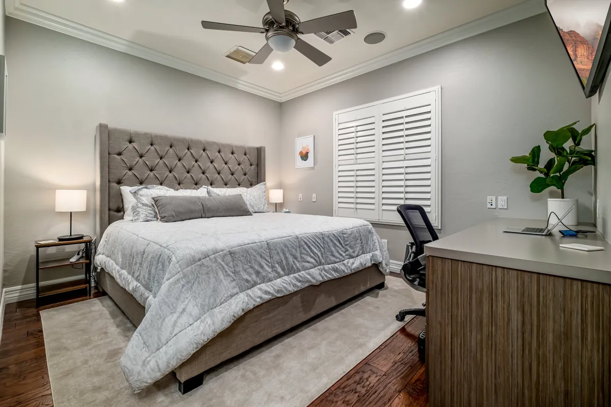 A bedroom featuring a tufted headboard king bed, a nightstand with lamp, and a dedicated desk with chair—ideal for guests needing a workspace or additional privacy.