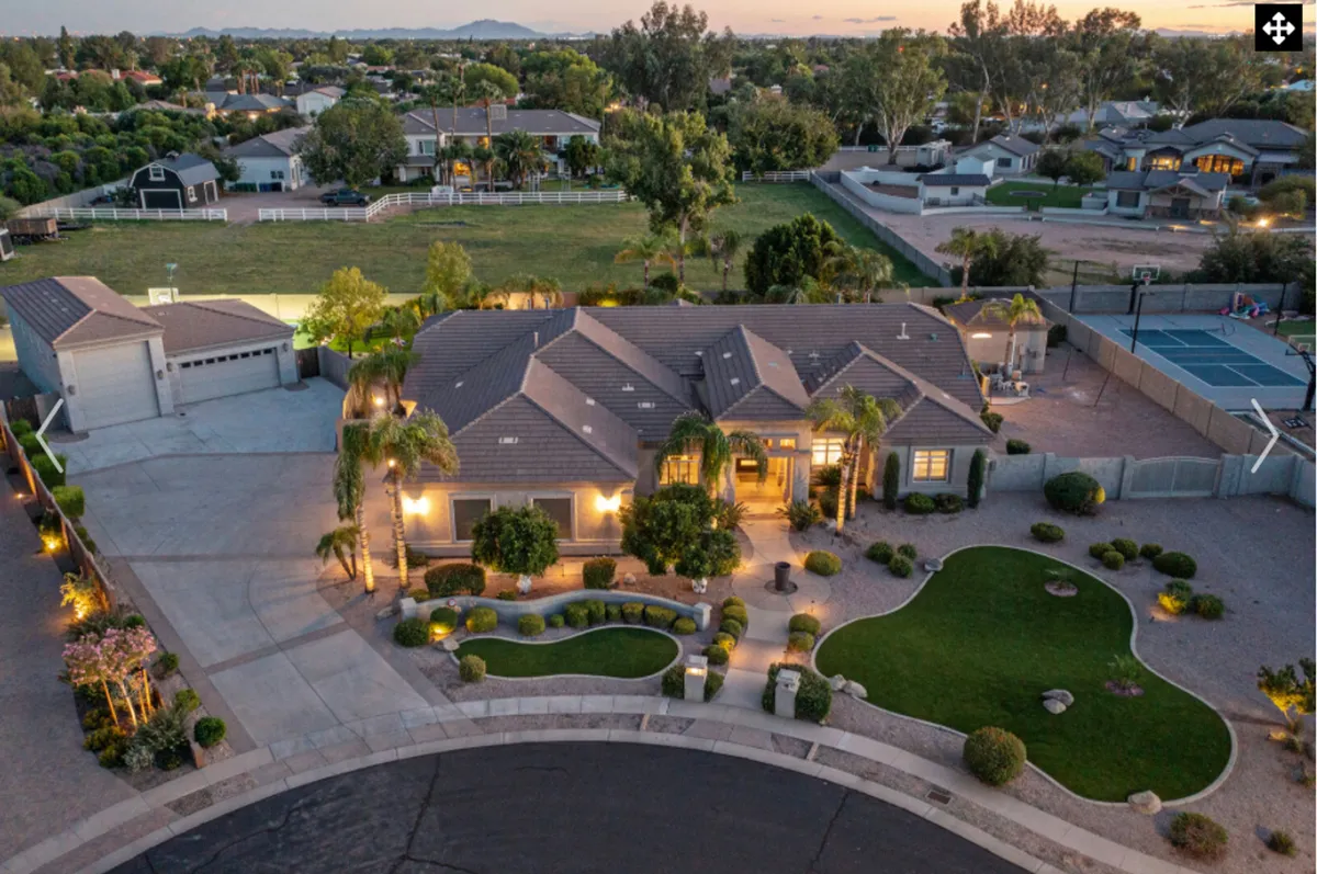 A wide-angle view of the house with a landscaped garden, pool area, and driveway. The scene is set during sunset, creating a welcoming and serene atmosphere that emphasizes the property’s curb appeal and outdoor living potential.
